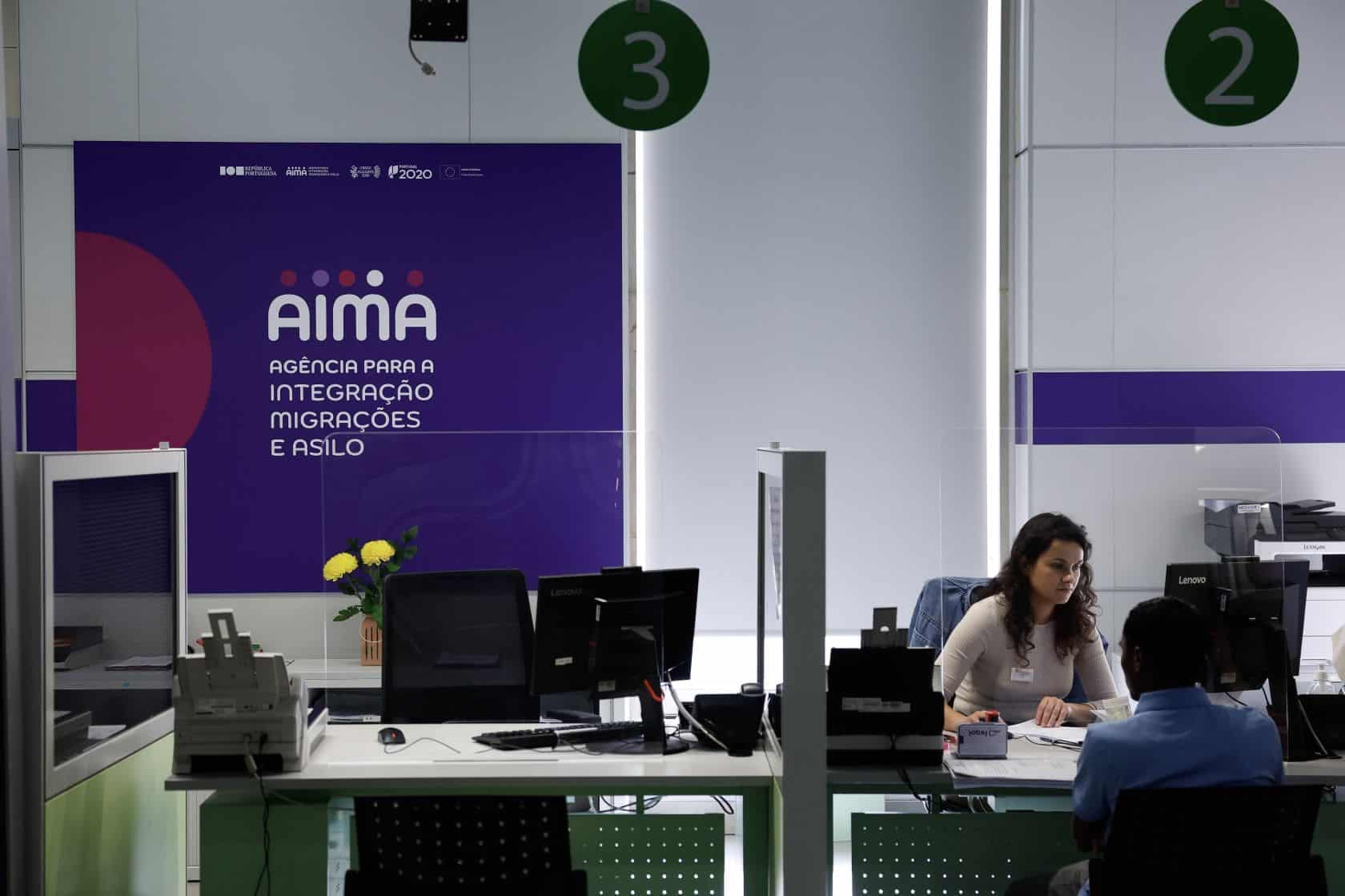 Public service hall at an AIMA office (the Portuguese immigration agency) — numbered service desks and a clerk sitting at a computer