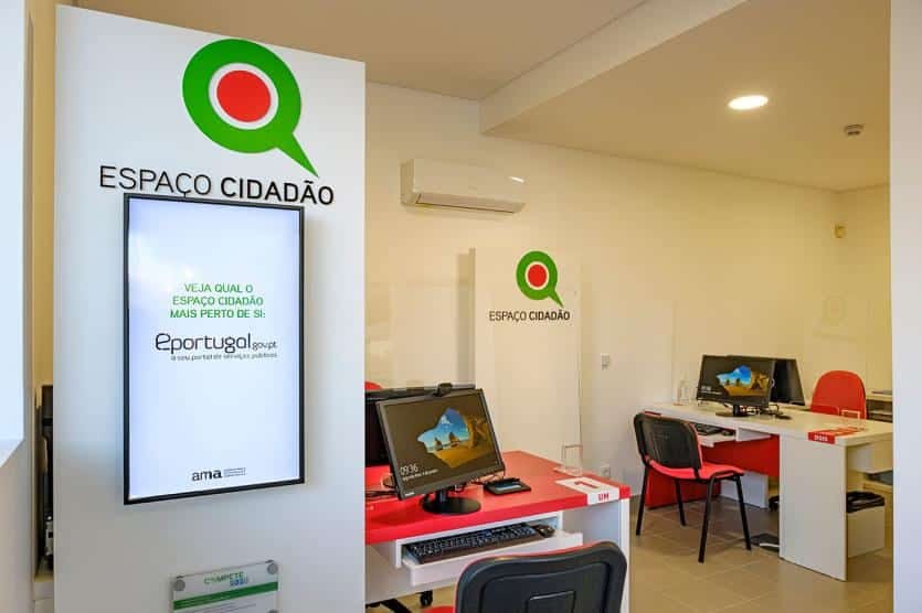 An Espaço Cidadão citizen service point — green-and-red sign, information screen, computers and a counter in a modern space