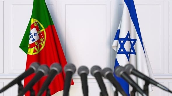 The flags of Portugal and Israel behind microphones at a press-conference lectern