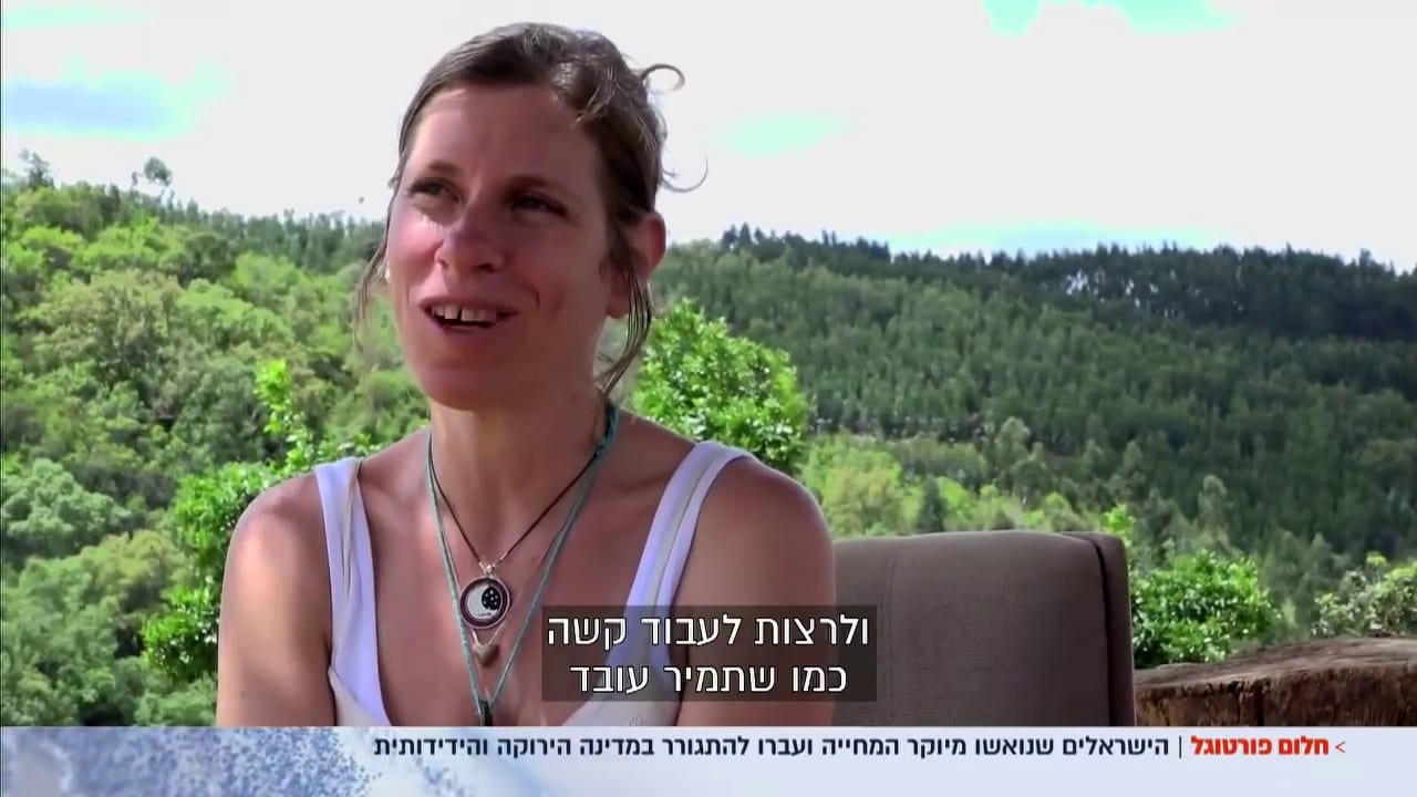Still from a video interview with a woman about moving to Portugal, filmed outdoors against a green forest